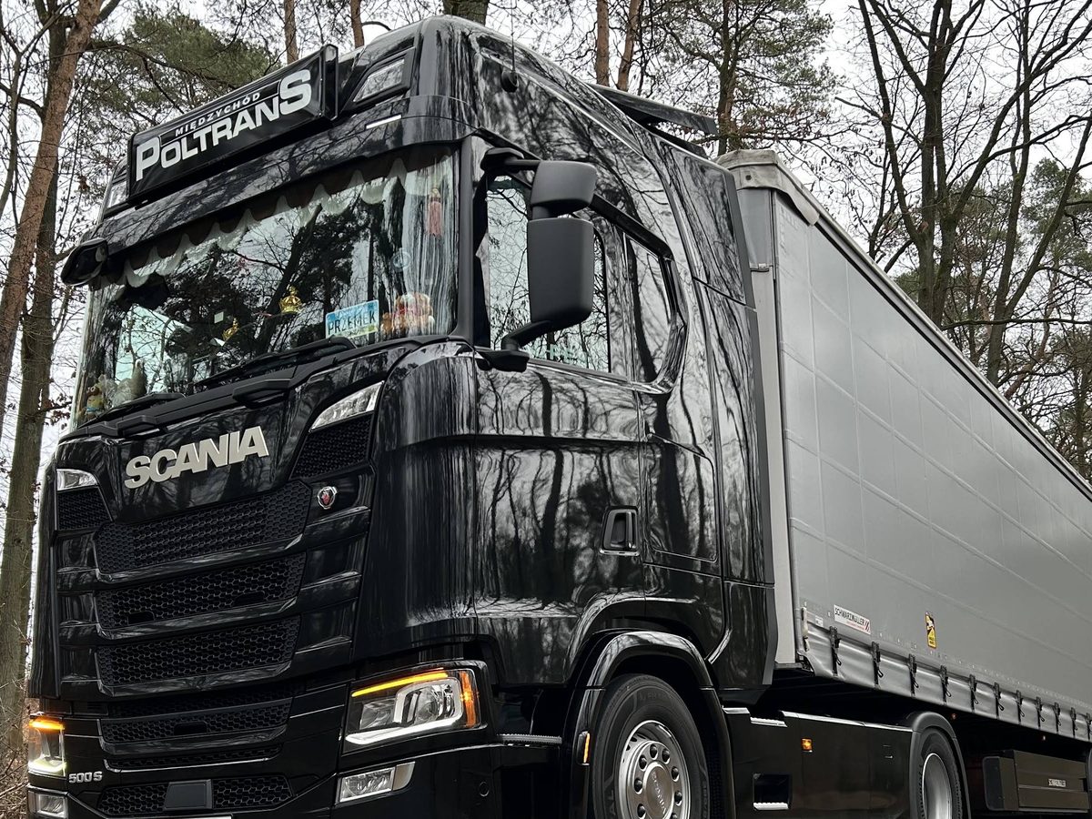 Kabina czarnej Scanii z podświetlanym szyldem POLTRANS Międzychód